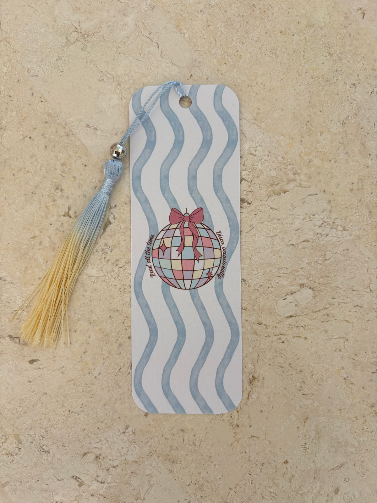 A rectangular bookmark with blue wavy lines, a disco ball illustration, and a blue and yellow tassel.