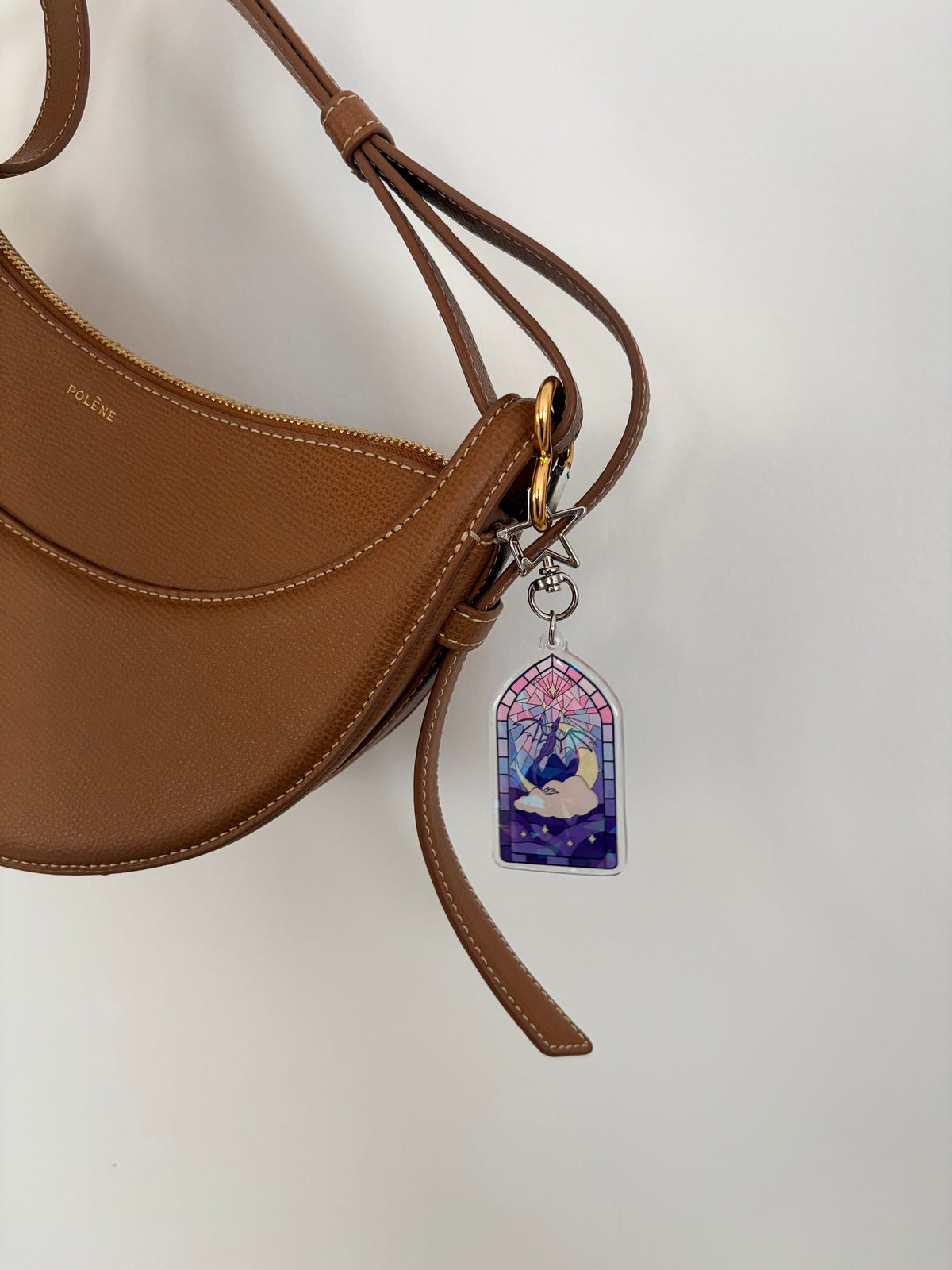 Stained glass style acrylic keychain attached to a brown leather handbag