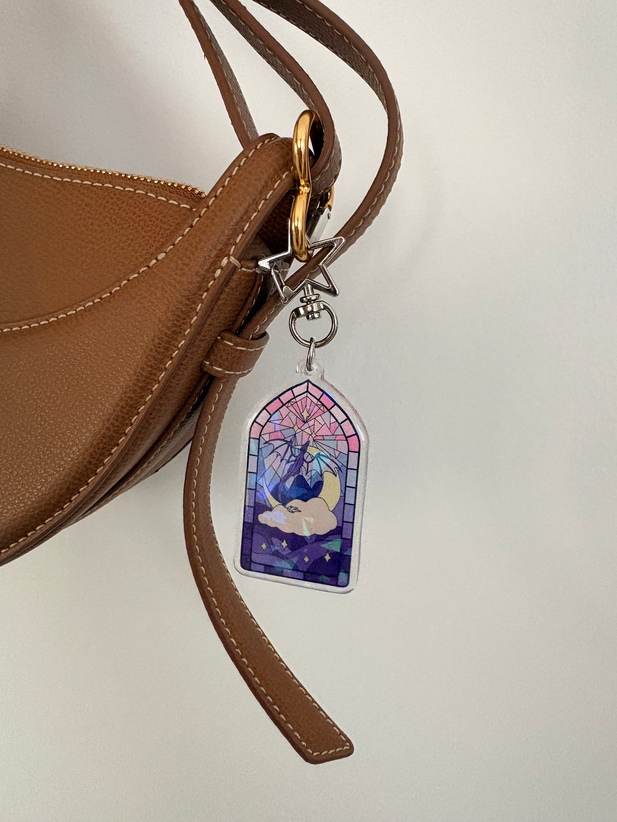Stained glass window acrylic keychain attached to a brown leather handbag