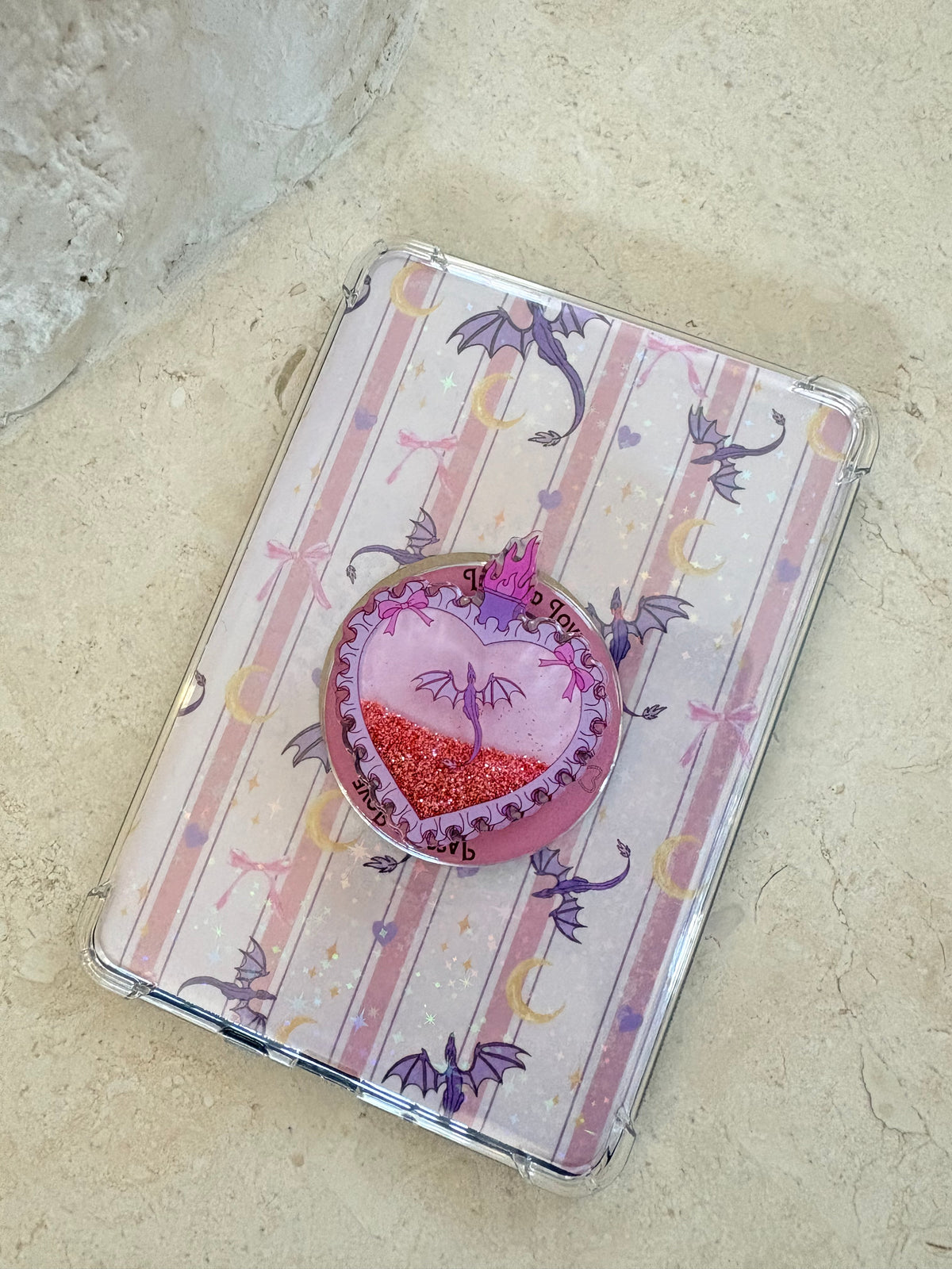 Pink striped Kindle insert with purple dragons and a matching heart-shaped Kindle grip.